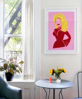 small dining table in New York apartment with sunflowers, Dolly Parton artwork and large window