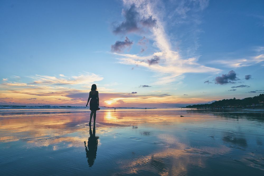 A silhouette of a woman walking on the beach.