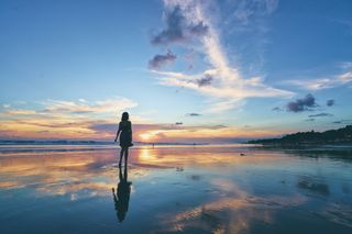 A silhouette of a woman walking on the beach.