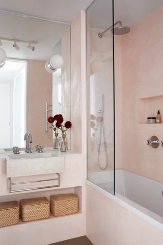 a pink bathroom with a shower over a bath