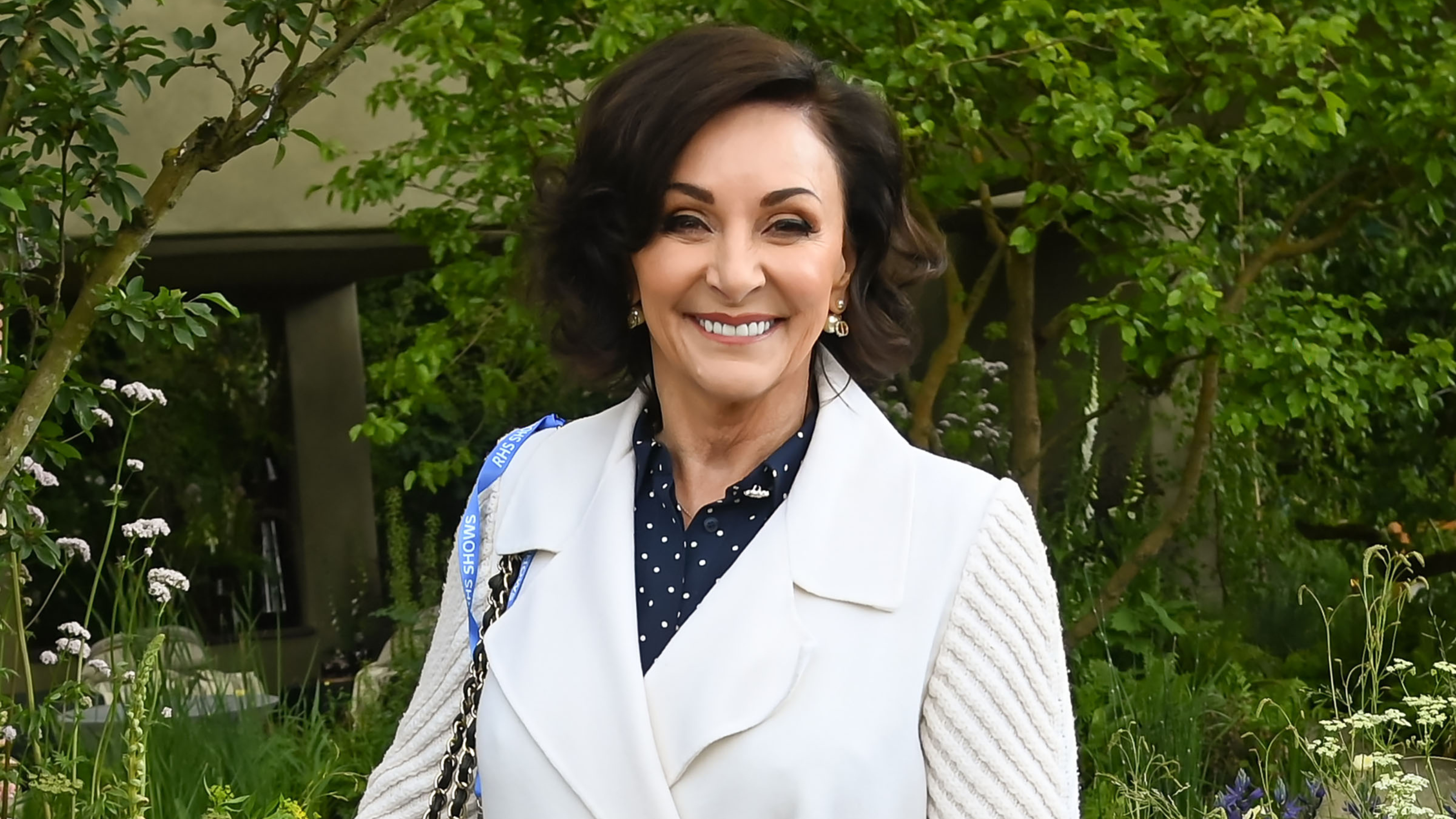 Shirley Ballas in white coat, with blue polka dot shirt underneath at Chelsea Flower Show.