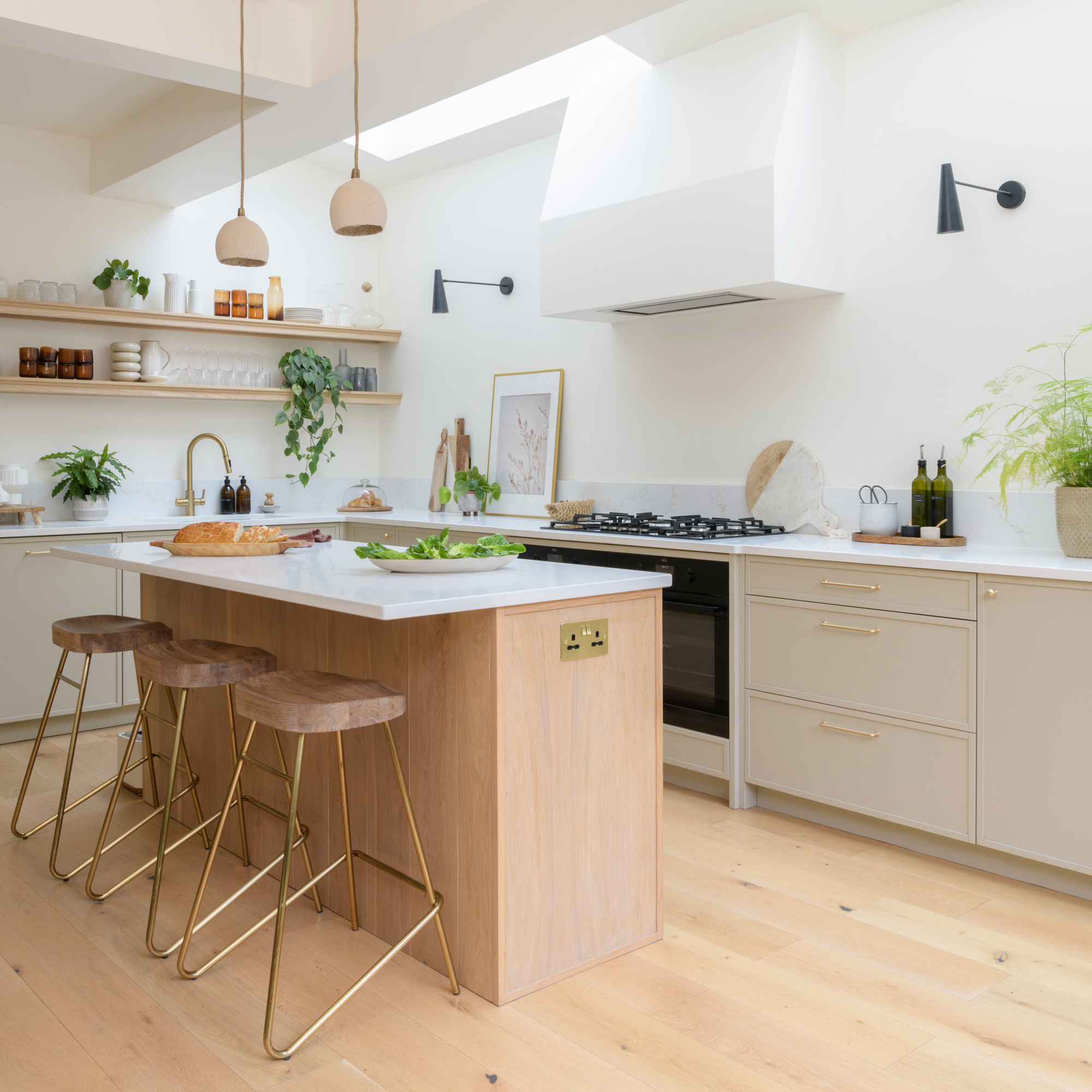 a bright and airy open plan kitchen with wooden flooring and a wooden kitchen island with pale worktops and neutral cabinetry