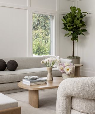 Neutral living room with sofa, armchairs, light wood coffee table and neutral rug