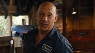 Vin Diesel having a happy conversation in his garage while wearing his work shirt in Fast X.