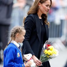 Catherine, Princess of Wales helps a schoolgirl lay her floral tribute at the entrance to Sandringham House, the Norfolk estate of Queen Elizabeth II, on September 15, 2022 in Sandringham, England. The Prince and Princess of Wales are visiting Sandringham to view tributes to Queen Elizabeth II, who died at Balmoral Castle on September 8, 2022.