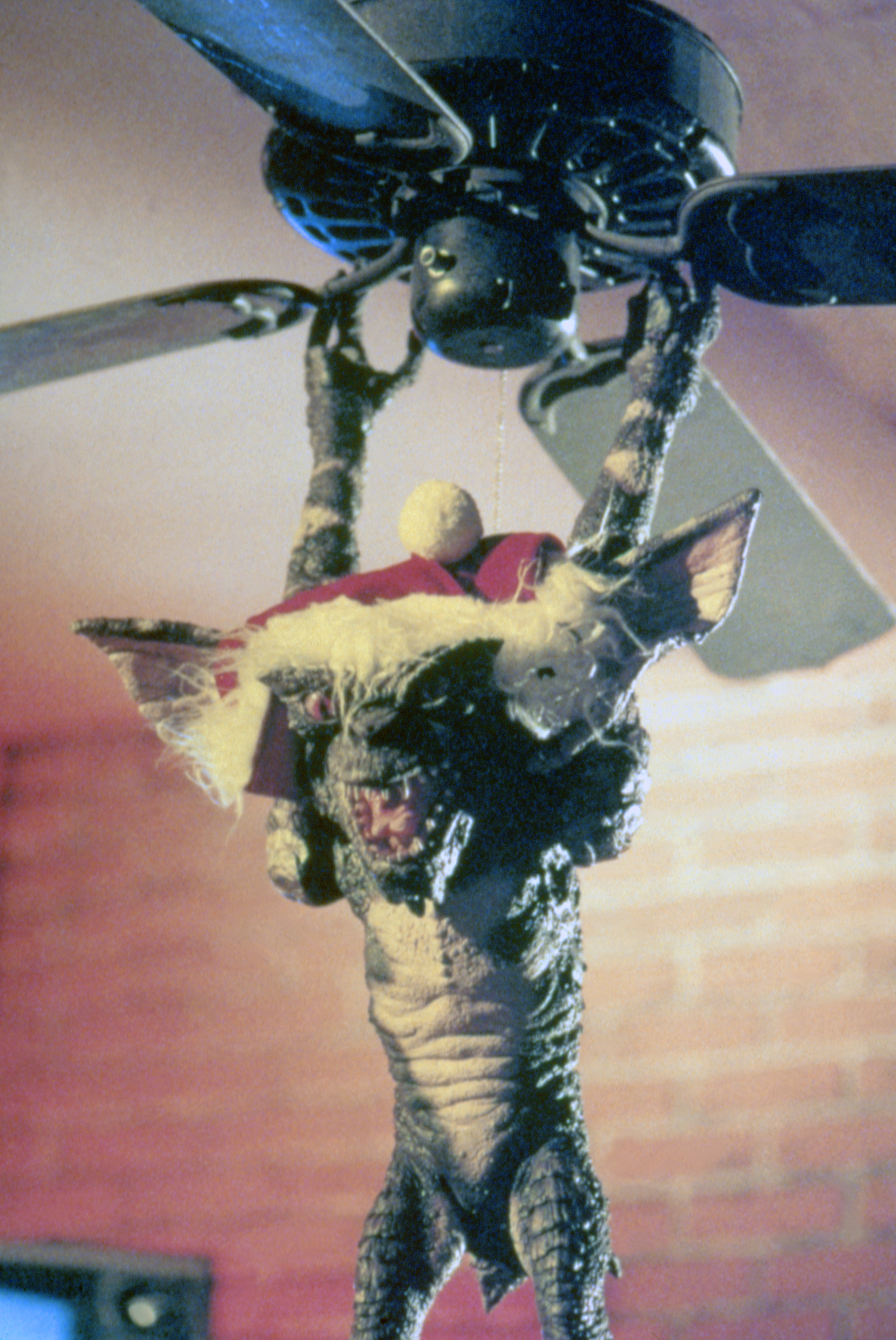 A photo of a gremlin hanging from a ceiling fan on the set of Gremlins.