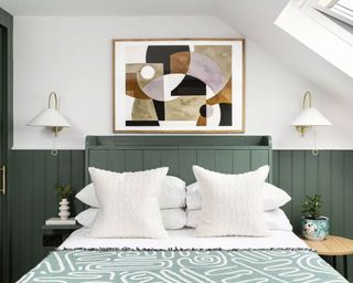 Bedroom with green paneling, two matching wall lights, artwork above bed