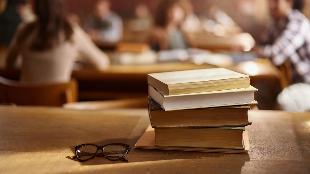 Pile of books and glasses on a wooden desk