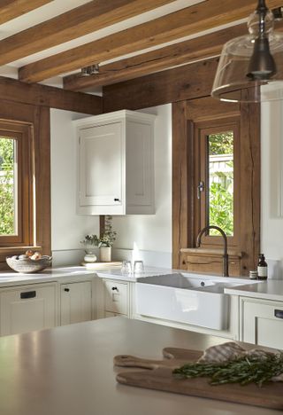 A small white kitchen with oak beams and oak windows frame.