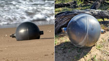 two large metallic spheres on a sandy beach