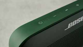 a green bluetooth speaker made by bose with a clean plastic casing and no visible woofers rests on a table