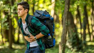 Man holding stomach in discomfort while hiking