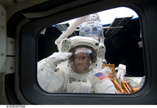 NASA astronaut Michael Good salutes during a spacewalk to upgrade the Hubble Space Telescope on May 15, 2009 during the space-based observatory's final servicing mission, STS-125.