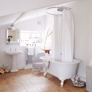 farmhouse exterior bathroom with stripped oak floor sets white rolltop bath and washstand basin and shower curtain