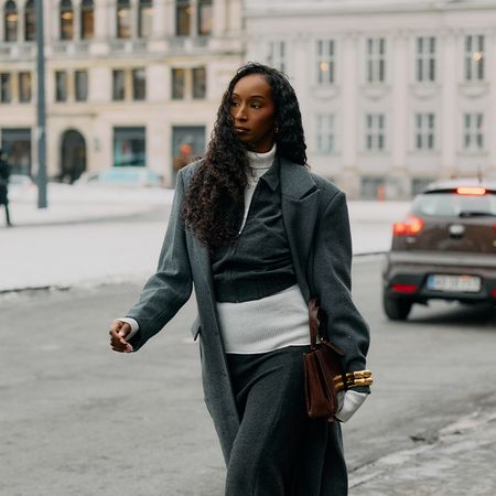 Woman wears light layers and a huge coat. 