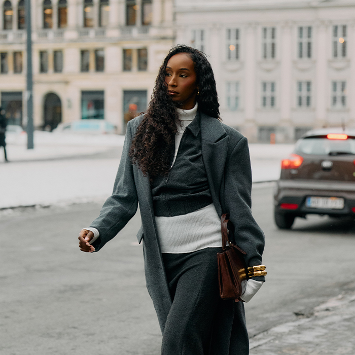 Woman wears light layers and a huge coat. 