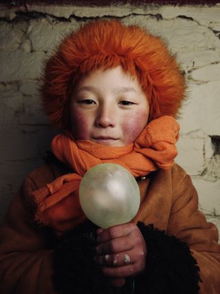 Un enfant aux cheveux orange tenant un ballon
