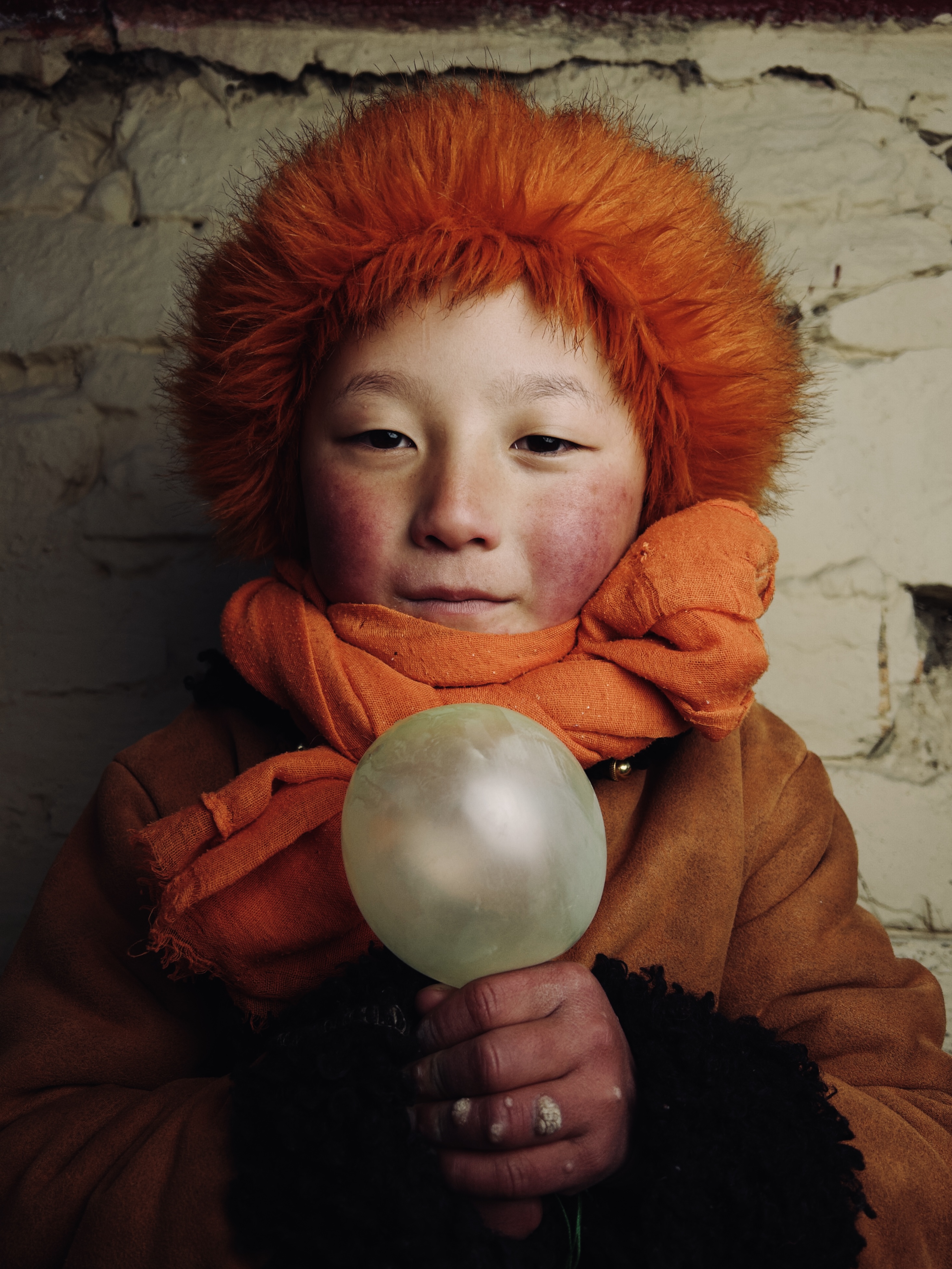 A child with orange hair holding a balloon