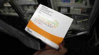 A pharmacist holds a box with flu shot vaccines (influenza vaccine package of Flucelvax quadrivalent) in an arranged photograph at a CVS Health Corp.