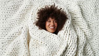 A woman wrapped in a Bearaby weighted blanket