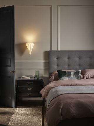 earth coloured bedroom with textures, stone coloured walls, grey headboard, black side table, coir rug, porcelain wall light