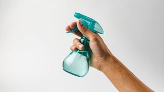 A filled spray bottle being held in a hand