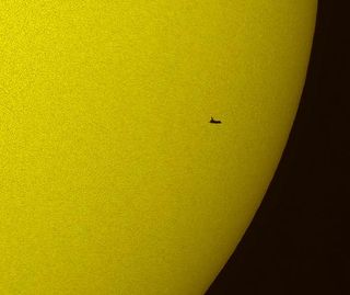 NASA Space Shuttle Atlantis silhouetted against Sun during solar transit from Florida.