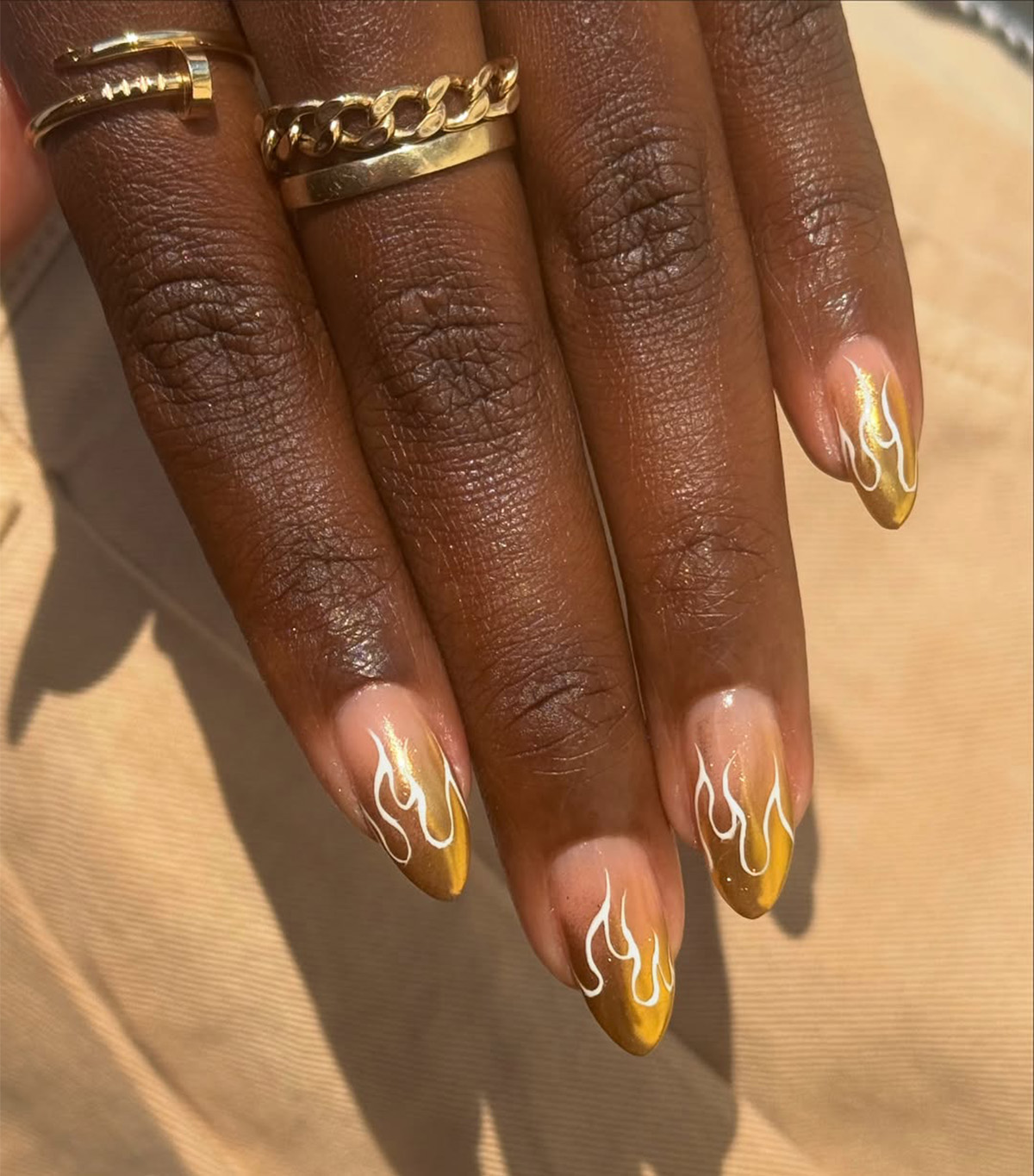 A chrome French manicure with gold flame details by Queenie Nguyen.