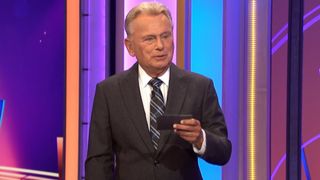 Pat Sajak reading a note card on Wheel of Fortune.