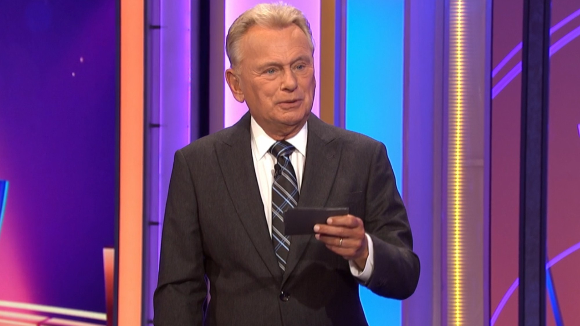 Pat Sajak reading a note card on Wheel of Fortune.