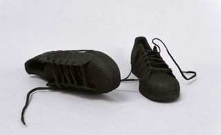 A pair of black shoes with laces, one lying on its side, named: Superstars, 2015
