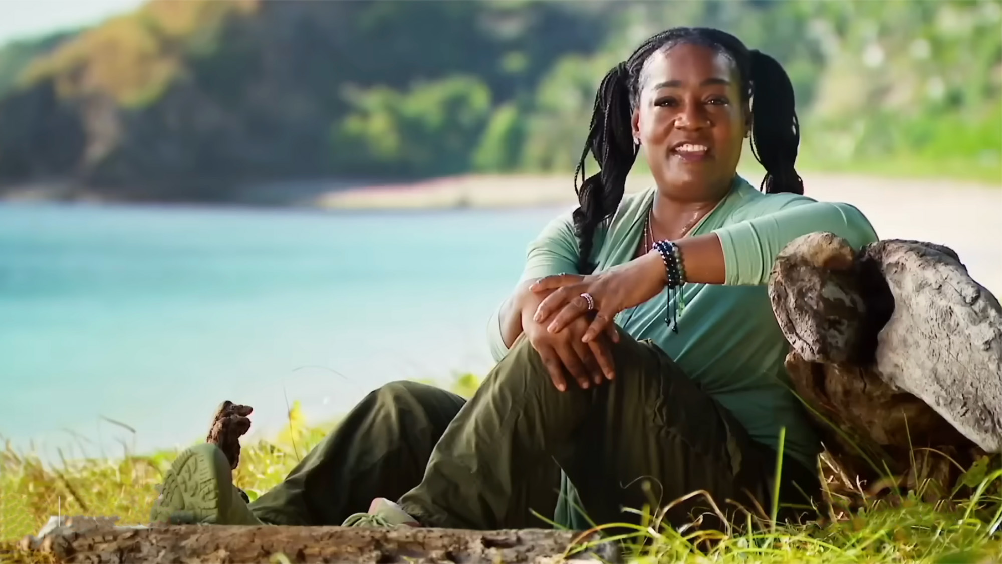 Cirie sits by a rock with a gorgeous view of Fiji in the background for a confessional on Survivor. 