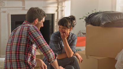 A couple looks at each other happily moving into a new home they bought. 