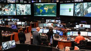 a room filled with computer monitors and large screens under the text "mission control center"