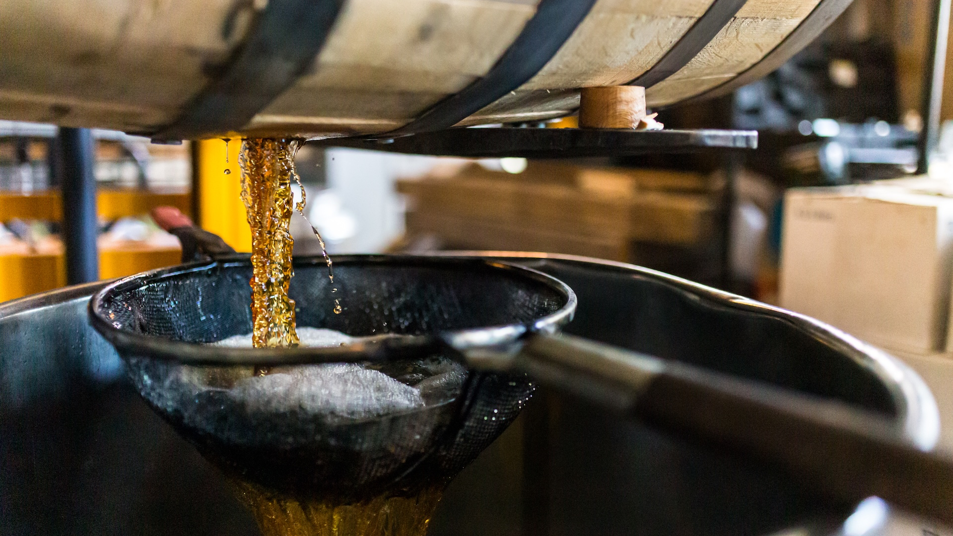 Bourbon Whiskey pouring from barrel into tank for bottling at distillery