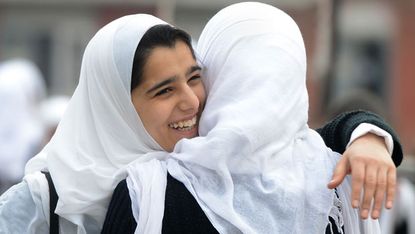 Two schoolgirls embrace and laugh