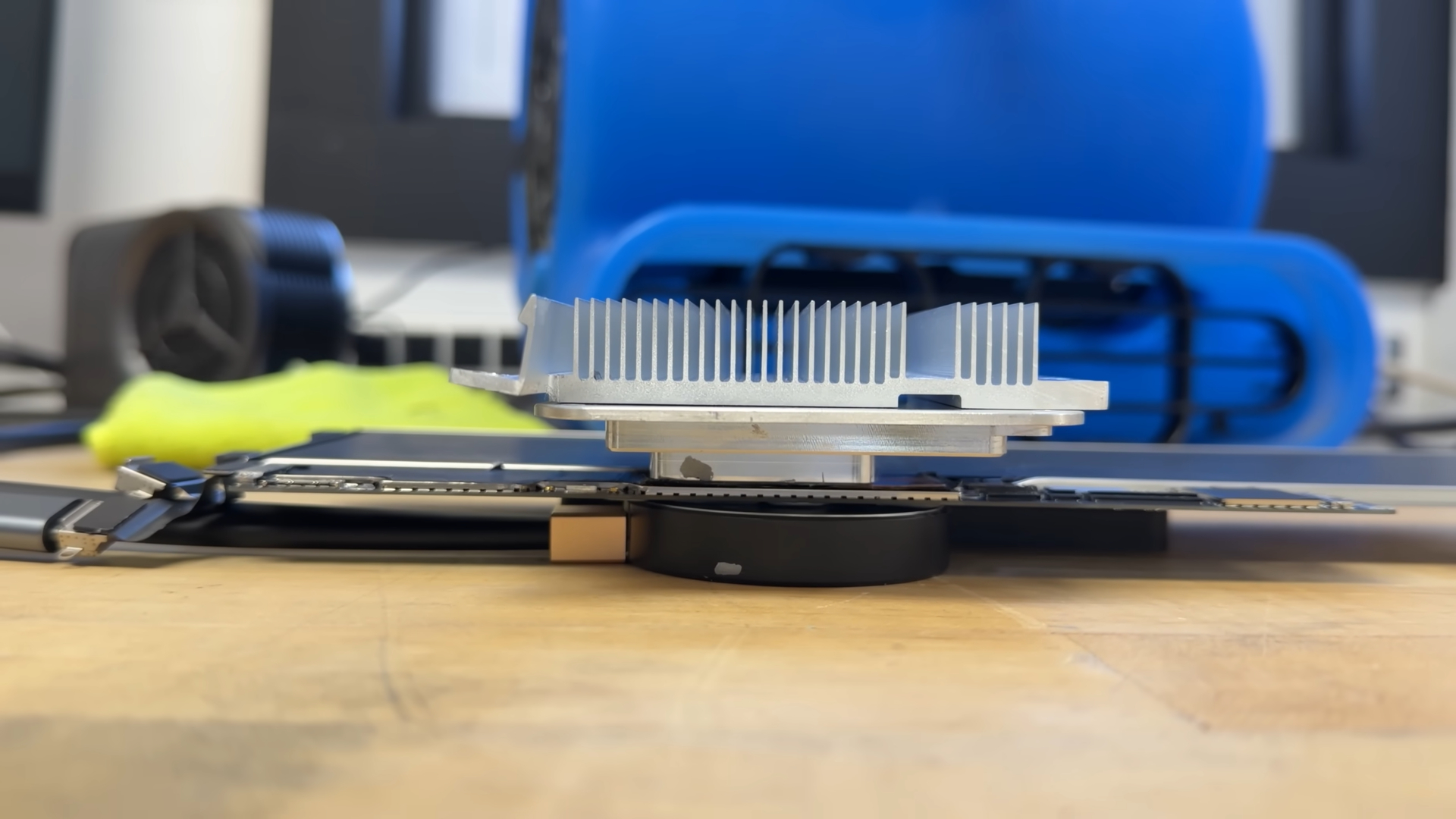 The A18 Pro chip from a MacBook Neo being cooled by a heatsink, industrial air blower, and a Peltier thermoelectric cooler.