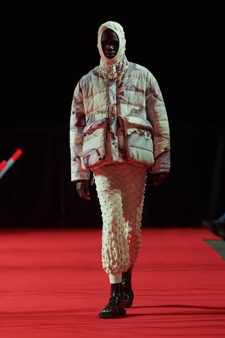 Man on Henrik Vibskov runway in puffer jacket with hood and knit trousers