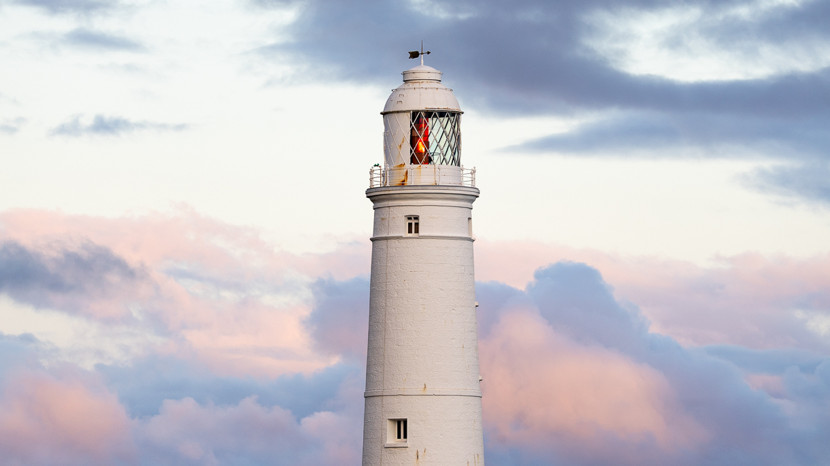 White lighthouse against pastel clouds