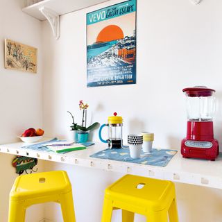 Breakfast bar against wall in kitchen with yellow metal bar stools
