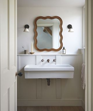 bathroom with large minimalist floating sink and wiggly edged wooden mirror