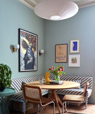 blue painted breakfast nook space with a striped banquette seat and large oversized pendant