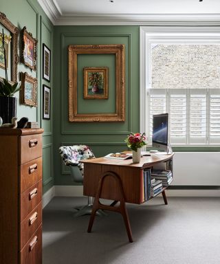 Home office with vintage desk and filing cabinet, neutral floor and green walls