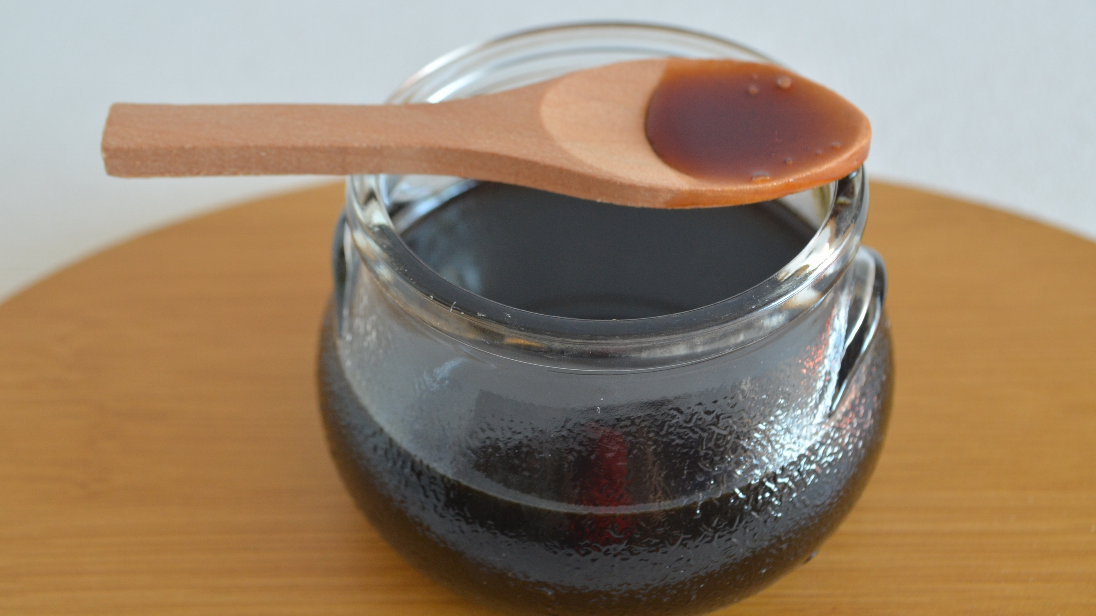 Glass jar of molasses with wooden spoon
