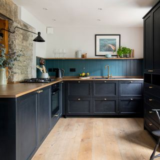 dark blue kitchen with wood worktops and black statement light
