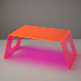 A neon pink acrylic laptop tray with slanted edges