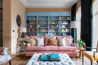 living room with a bespoke blue fitted bookshelf and pink sofa and cream walls