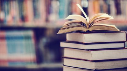 Books On Table Against Shelf In Library