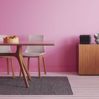 A hot pink dining room with wooden furniture