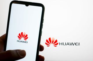 The Huawei logo is being displayed on a smartphone screen and on a computer screen